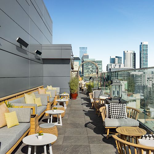 A modern rooftop terrace with comfortable seating, tables, and city skyline views, ideal for relaxation and social gatherings.